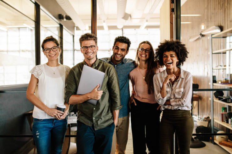 Portrait of creative business team standing together and laughing. Multiracial business people together at startup.