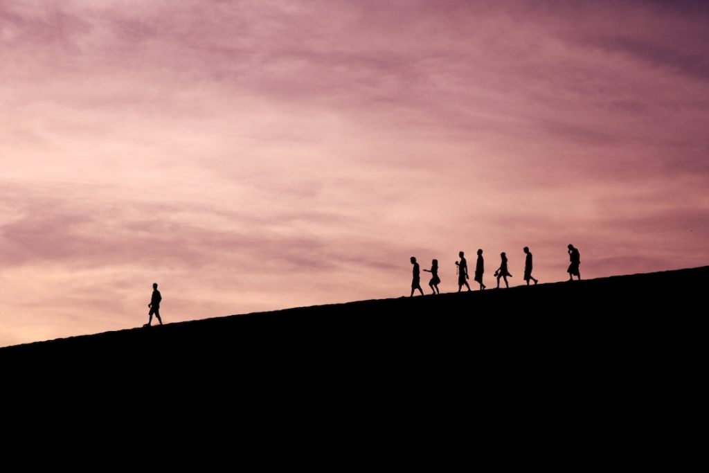 This picture show a group of people walking with the leader going first.