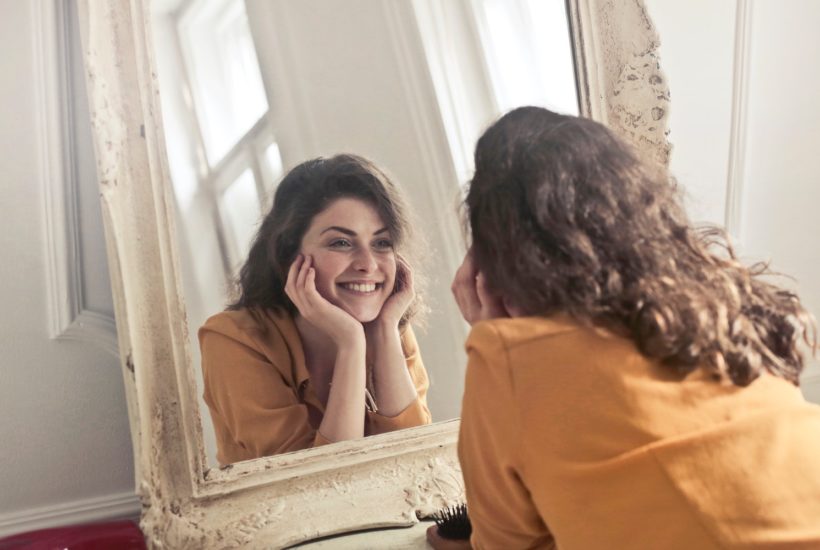 This picture show a woman looking at herself in a mirror.