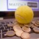 This picture show a tennis balls and some coins on top of a keyboard.