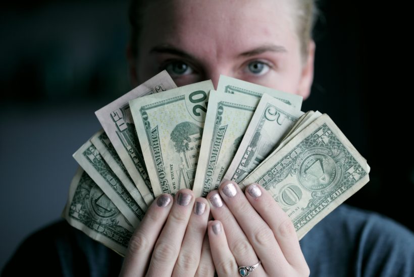 This picture show a person holding a couple of dollar bills.