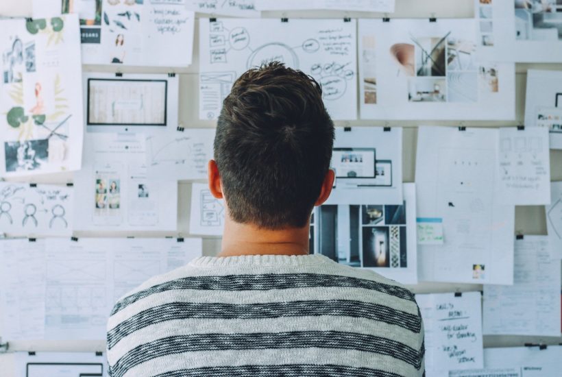 This picture show a man looking at some notes in a board.