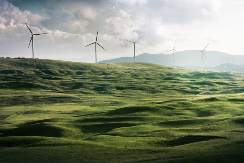 This picture shows a couple of wind turbine on a cliff.