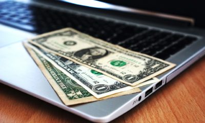 This picture show a couple of dollar bills on top of a laptop.