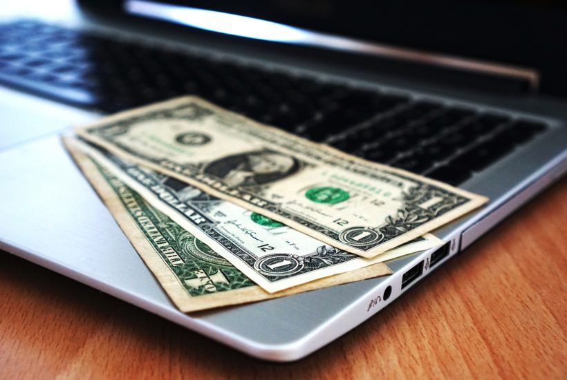 This picture show a couple of dollar bills on top of a laptop.