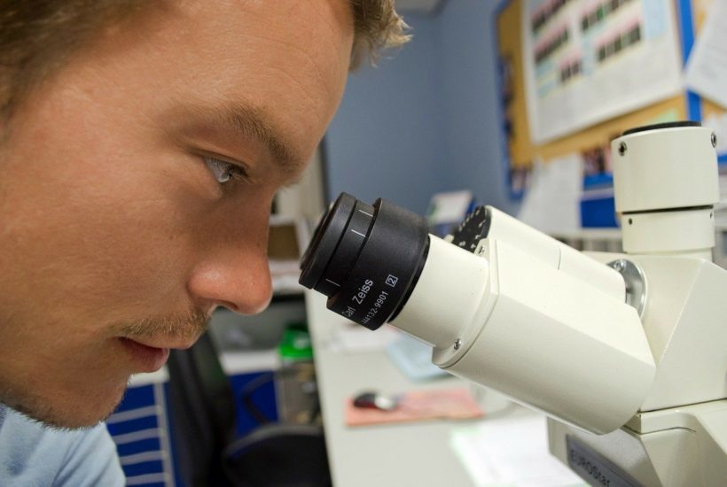 This picture show a person lookin through a microscope.