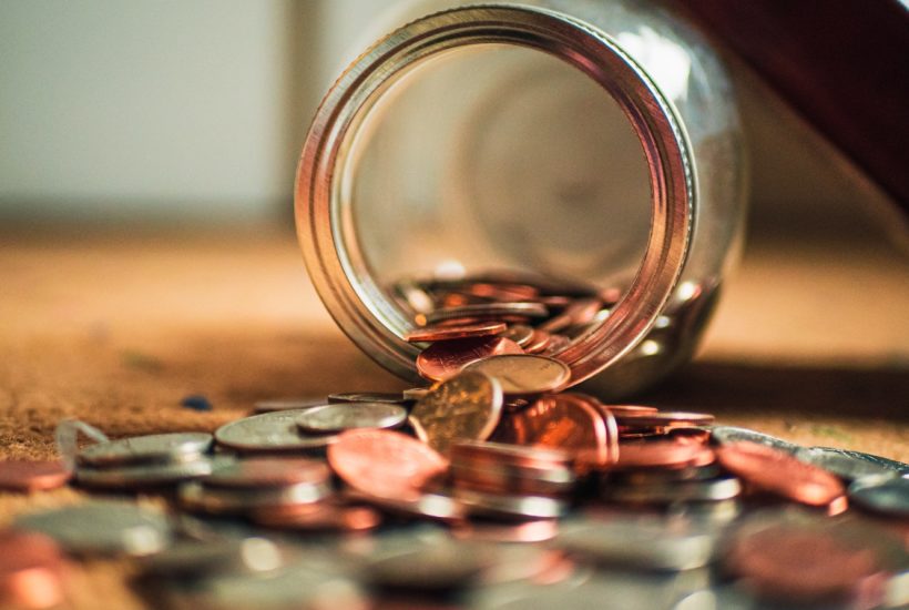 This picture show a bunch of coins pouring out of a bottle.