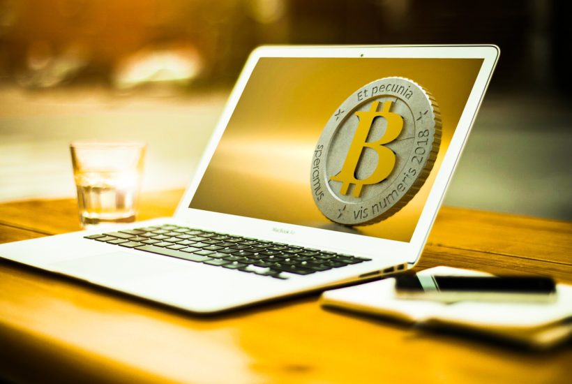 This picture show a laptop with a bitcoin in the screen.