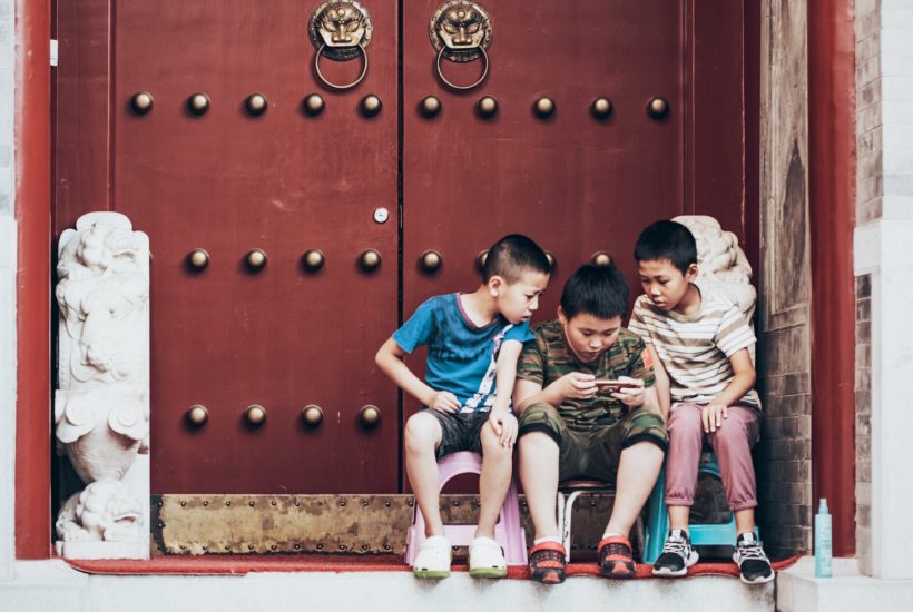 This picture show 3 kids playing with their phones.