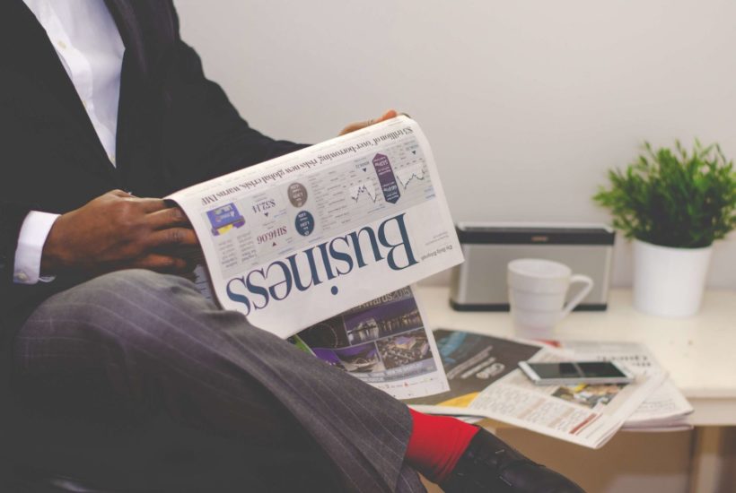 This picture show a man reading a newspaper.