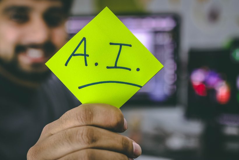 This picture show a persona holding a paper with the AI word written on it.