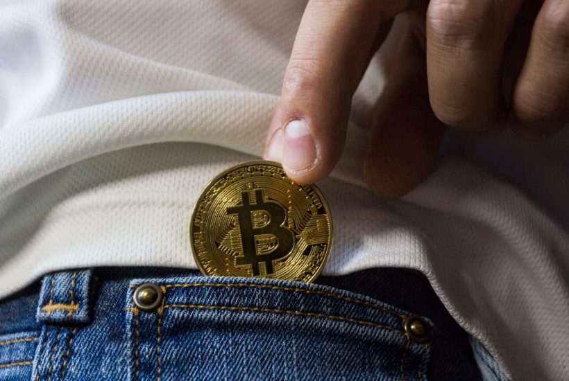 This picture show a persona putting a bitcoin in his pocket.