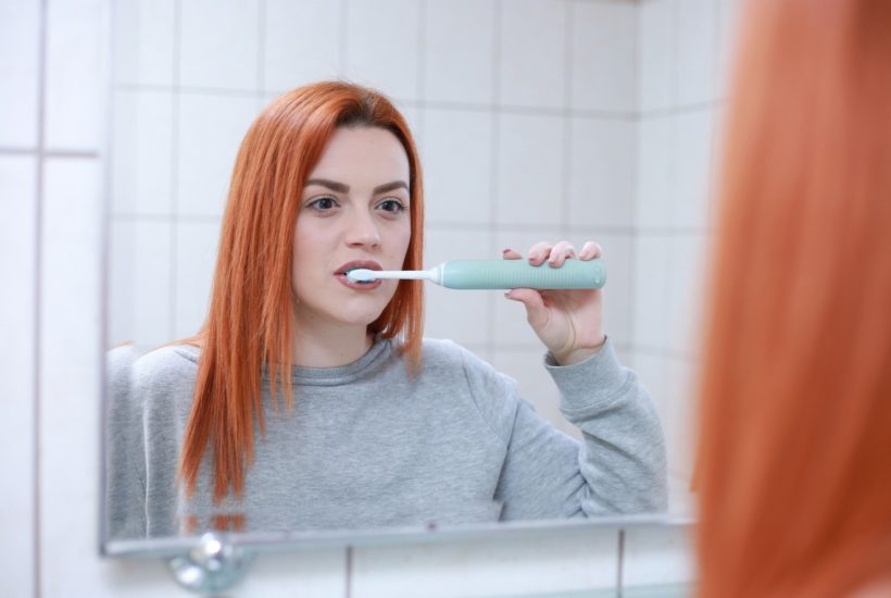 This picture show a woman brushing her teeths.